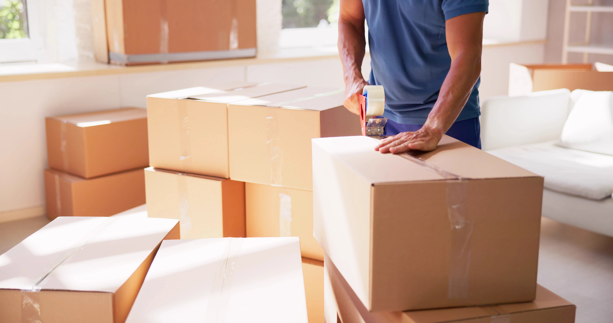 Man taping up piles of moving boxes.